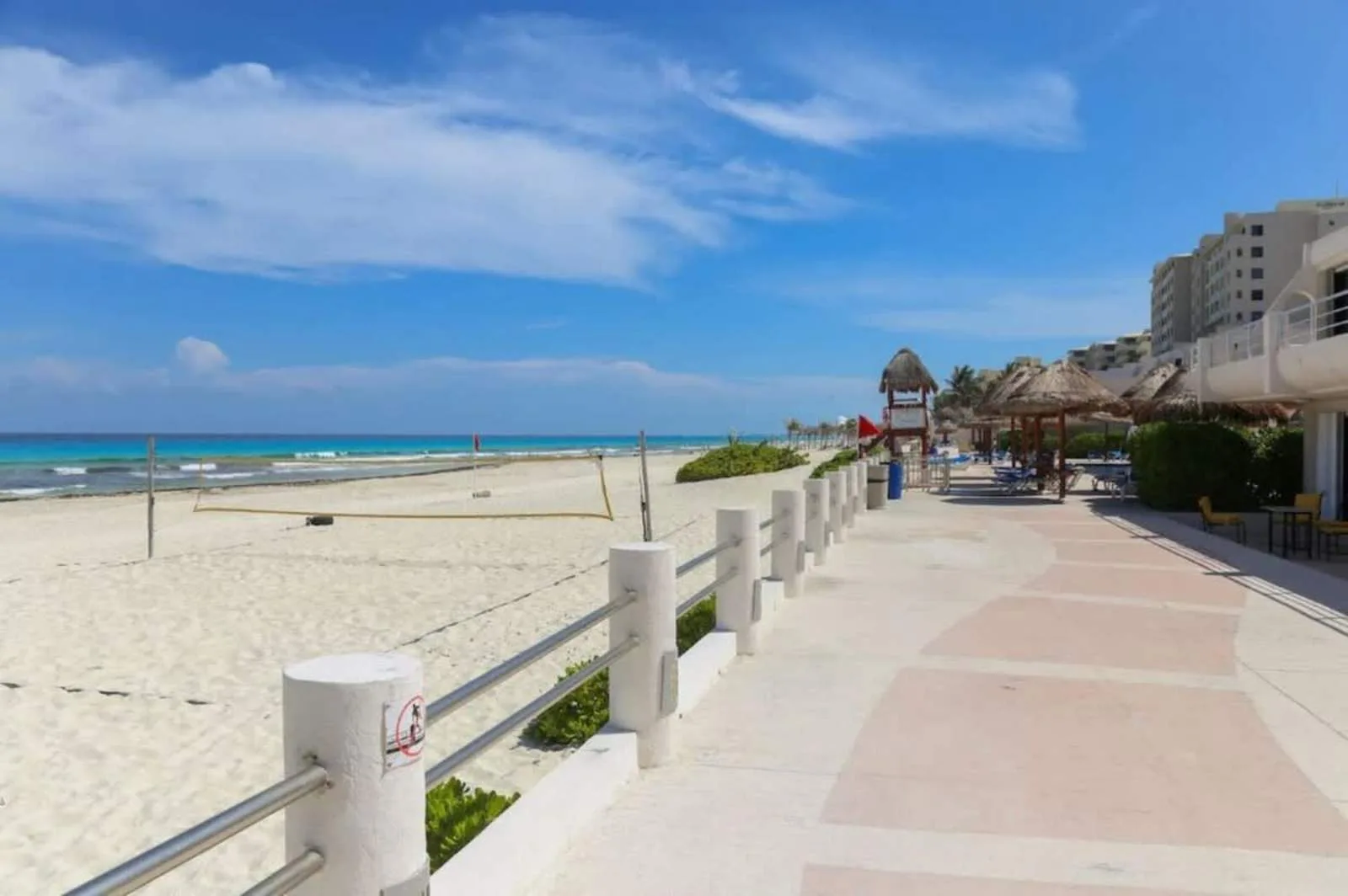 Shared amenity: A beachfront promenade runs beside a sandy beach and calm blue water.