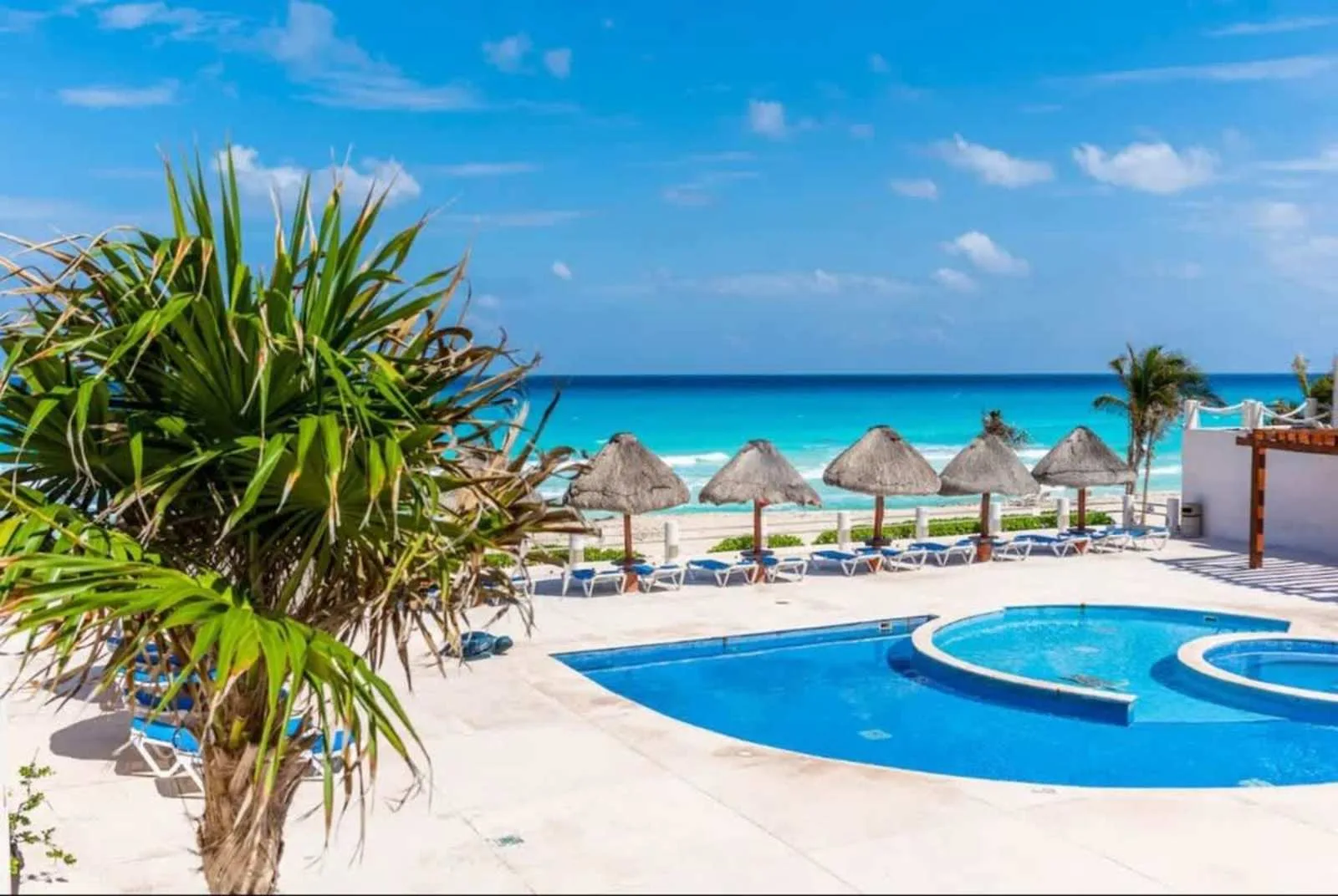 Shared amenity: A pool area overlooks a beach lined with thatched umbrellas.