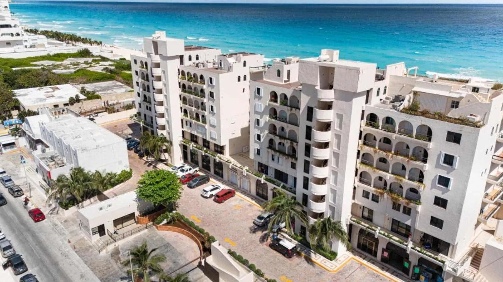 Zona común: Vista aérea de edificios de apartamentos junto a una costa turquesa.