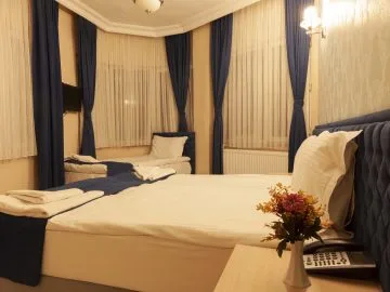 Espacio representativo del hotel: Dormitorio con una cama grande, una mesita de noche y ventanas altas con cortinas.
