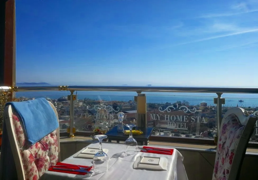 Espacio representativo del hotel: Una mesa puesta tiene vistas al mar desde una terraza con barandilla de cristal.