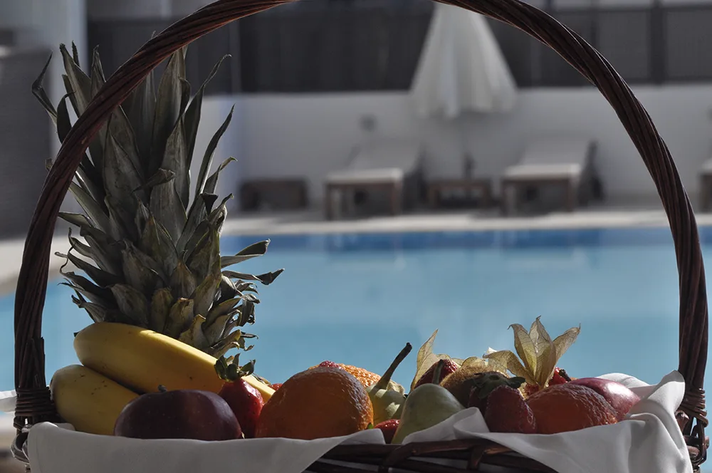 Representative hotel space: A basket of fruit sits beside a swimming pool.