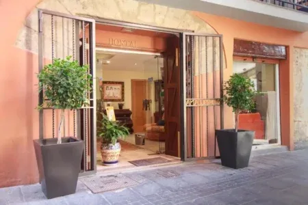 Espacio representativo del hotel: Entrada de hotel con las puertas abiertas y plantas en macetas junto a la puerta.