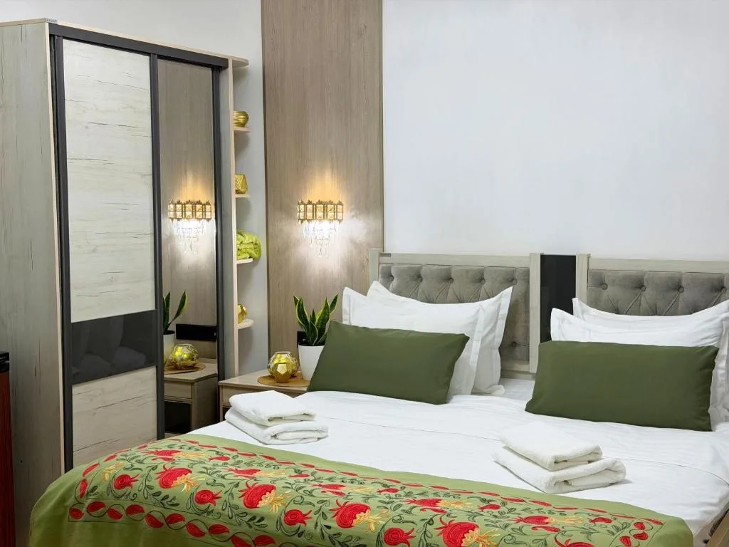 Representative hotel space: A bedroom with two beds dressed in white linens and green accents.