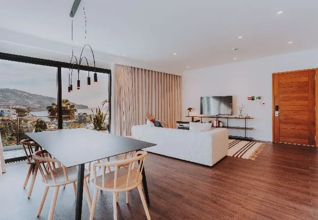 Una luminosa sala de estar y comedor de concepto abierto con grandes ventanas hacia el paisaje.