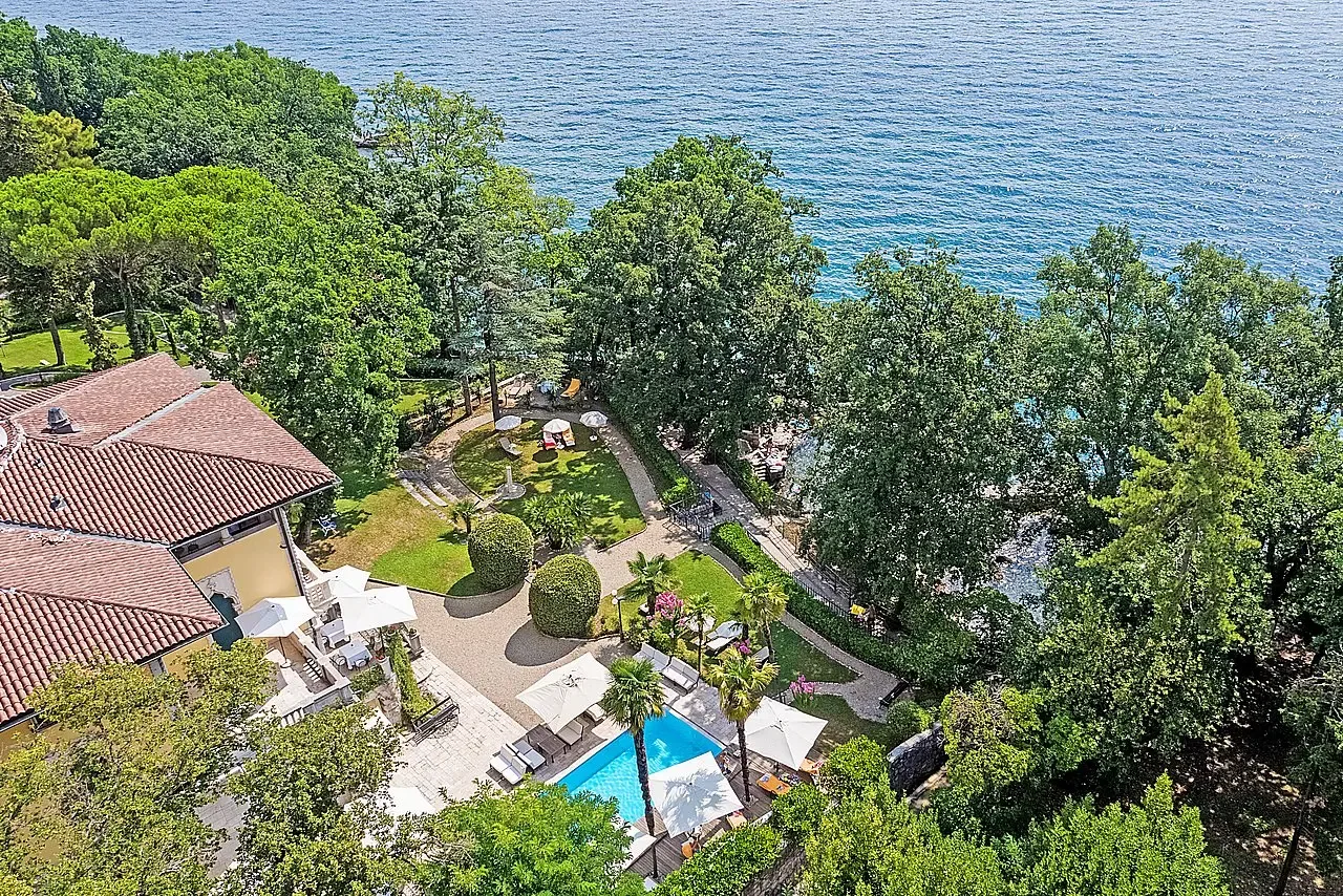 Representative hotel space: Aerial view of a landscaped hotel grounds beside the water, with a pool.