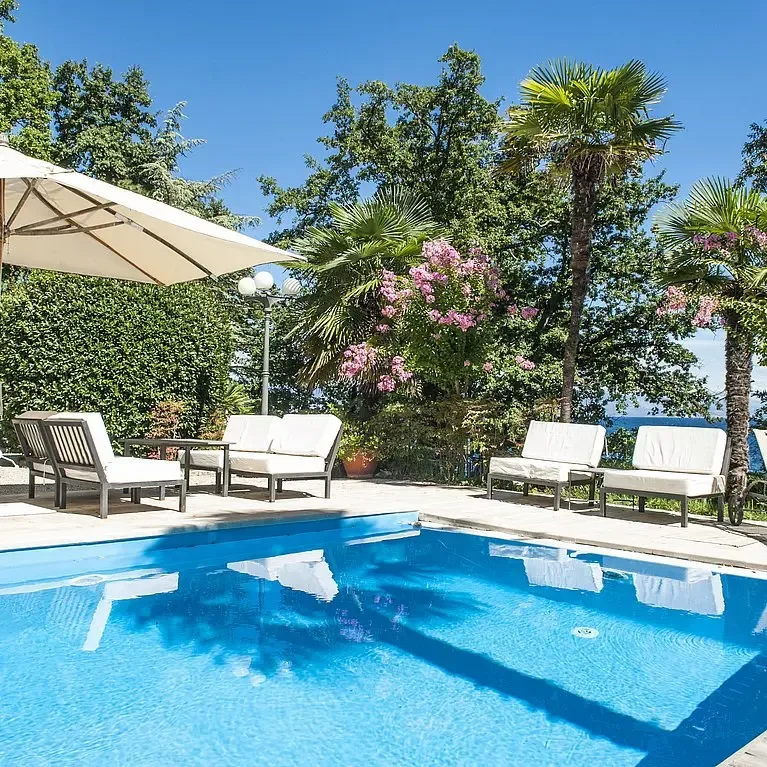 Representative hotel space: An outdoor swimming pool is surrounded by lounge seating and leafy plants.