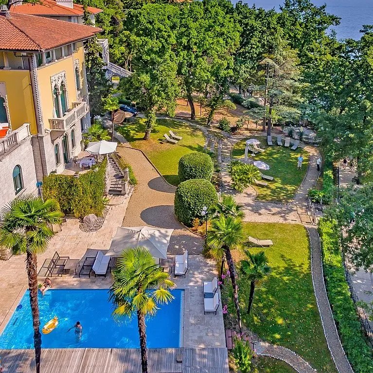 Representative hotel space: A hotel garden and pool beside a building, with lawns and trees.