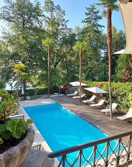 Representative hotel space: An outdoor swimming pool is surrounded by a wooden deck and greenery.