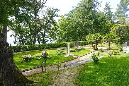 Representative hotel space: A landscaped garden with a winding path, lawn, trees, and outdoor seating.