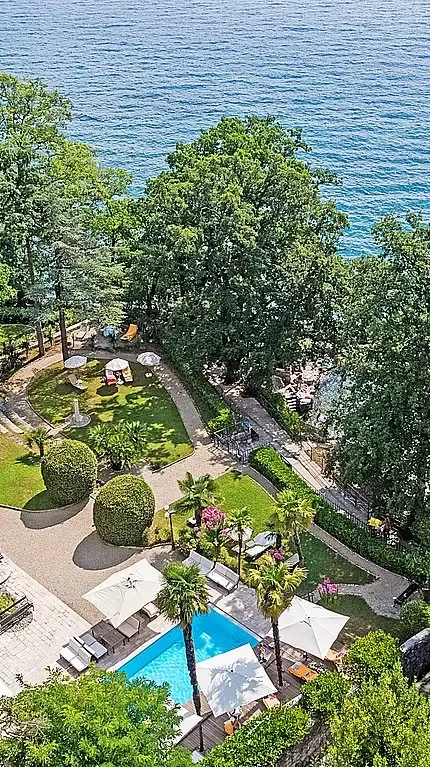 Representative hotel space: A landscaped pool area with seating and trees beside the water.