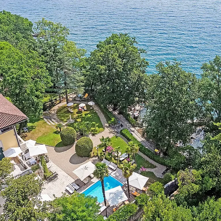 Representative hotel space: Aerial view of a waterfront garden with a swimming pool and seating areas.