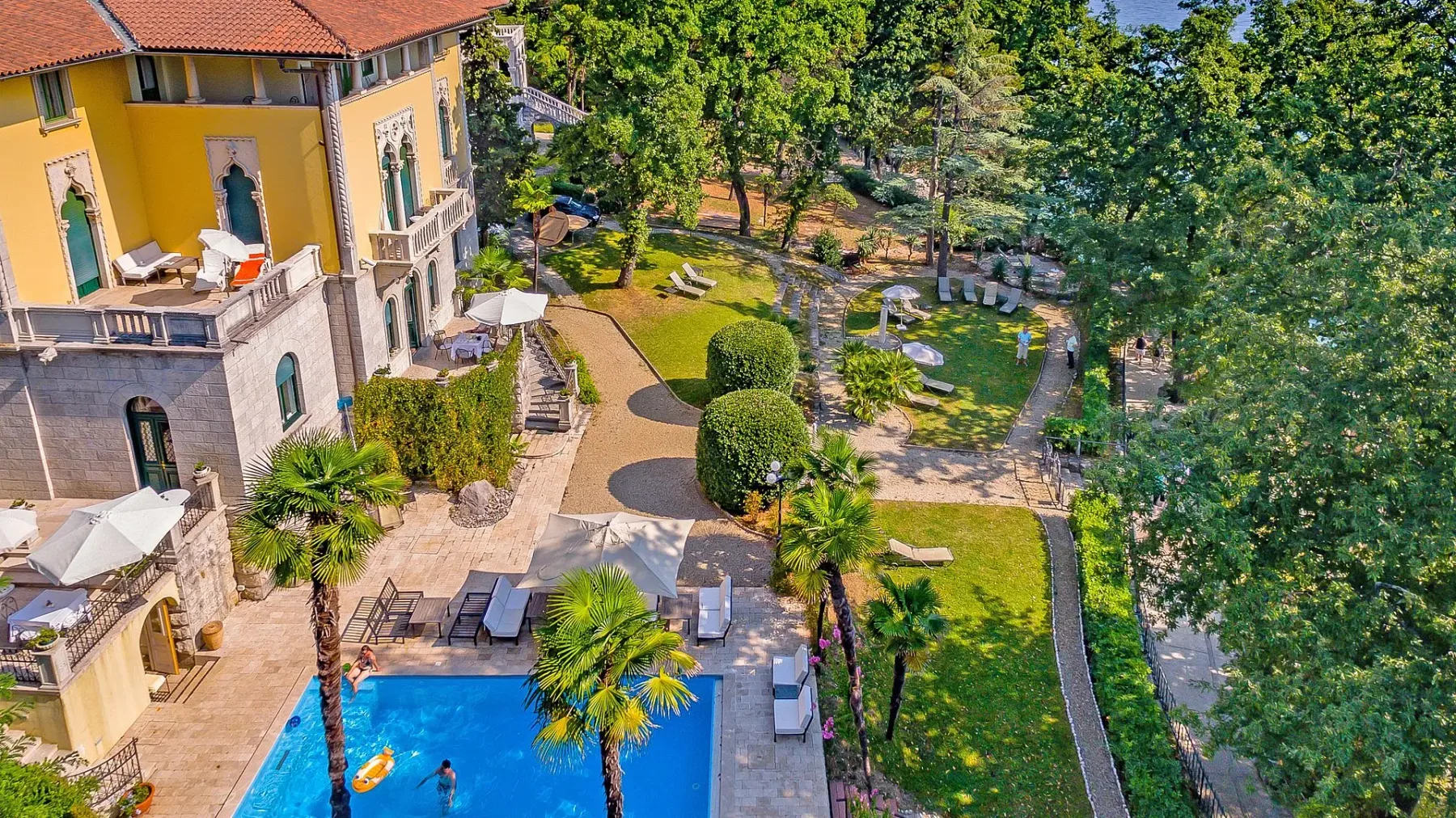 Representative hotel space: A landscaped courtyard with a swimming pool beside a yellow building.