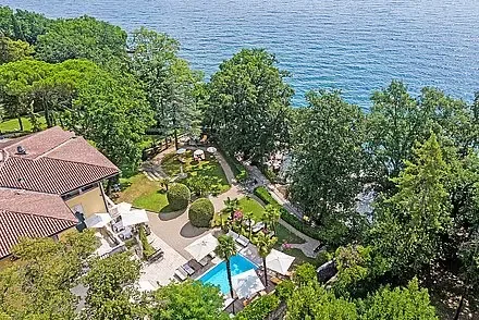 Representative hotel space: An aerial view of a garden, swimming pool, and buildings beside the sea.