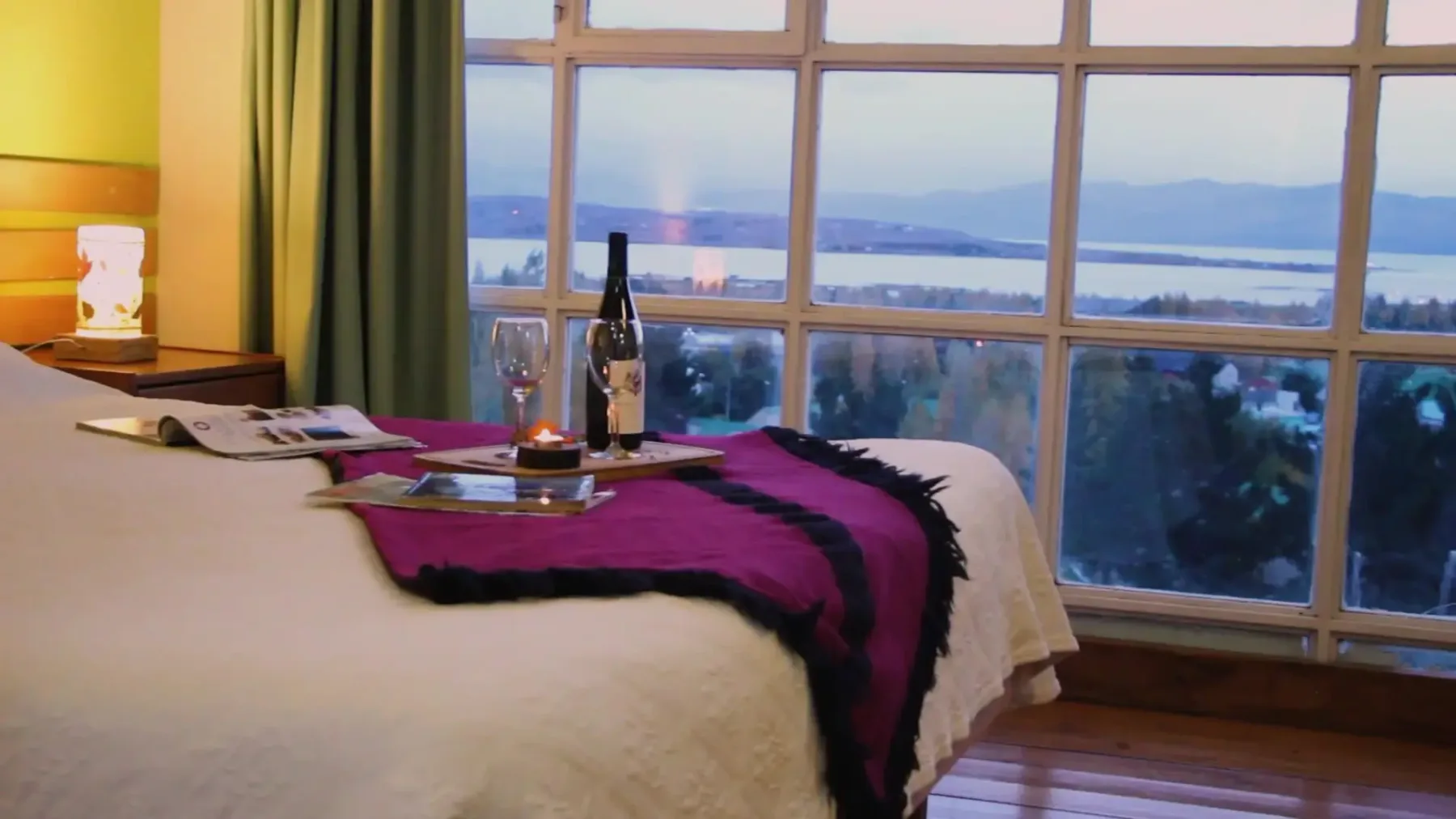 Representative hotel space: A bedroom with a bed set beside a large window overlooking the water.