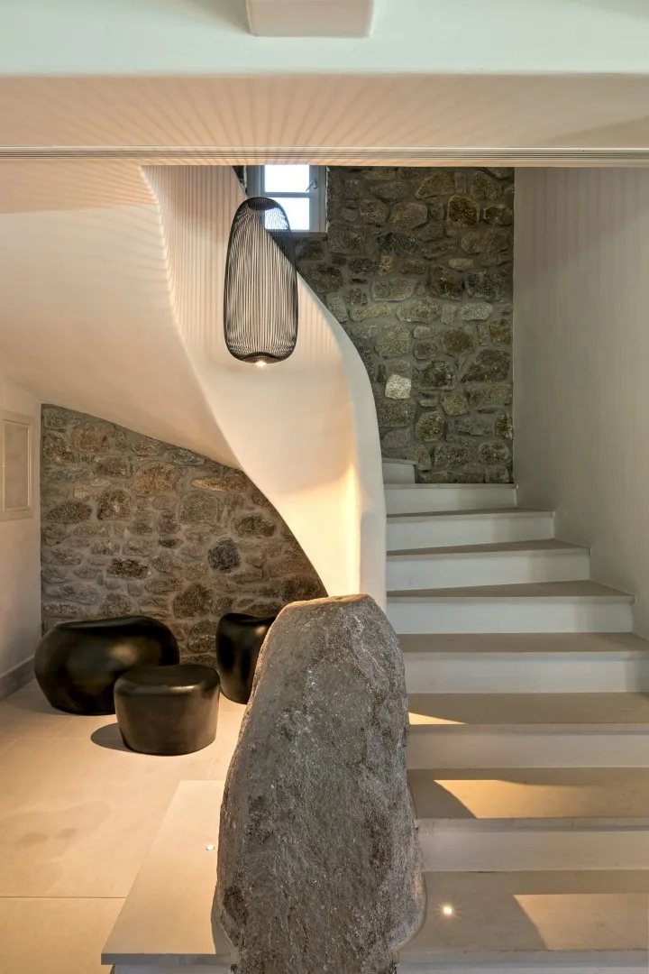 A stone staircase rises beside a curved wall and dark seating.