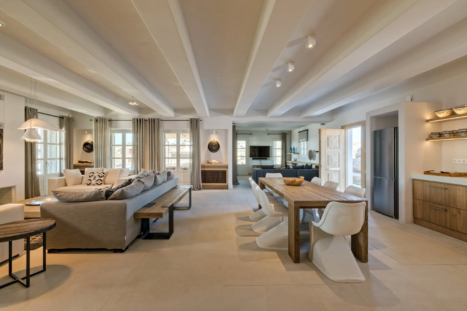 An open-plan living and dining room with seating, a long table, and a fireplace.