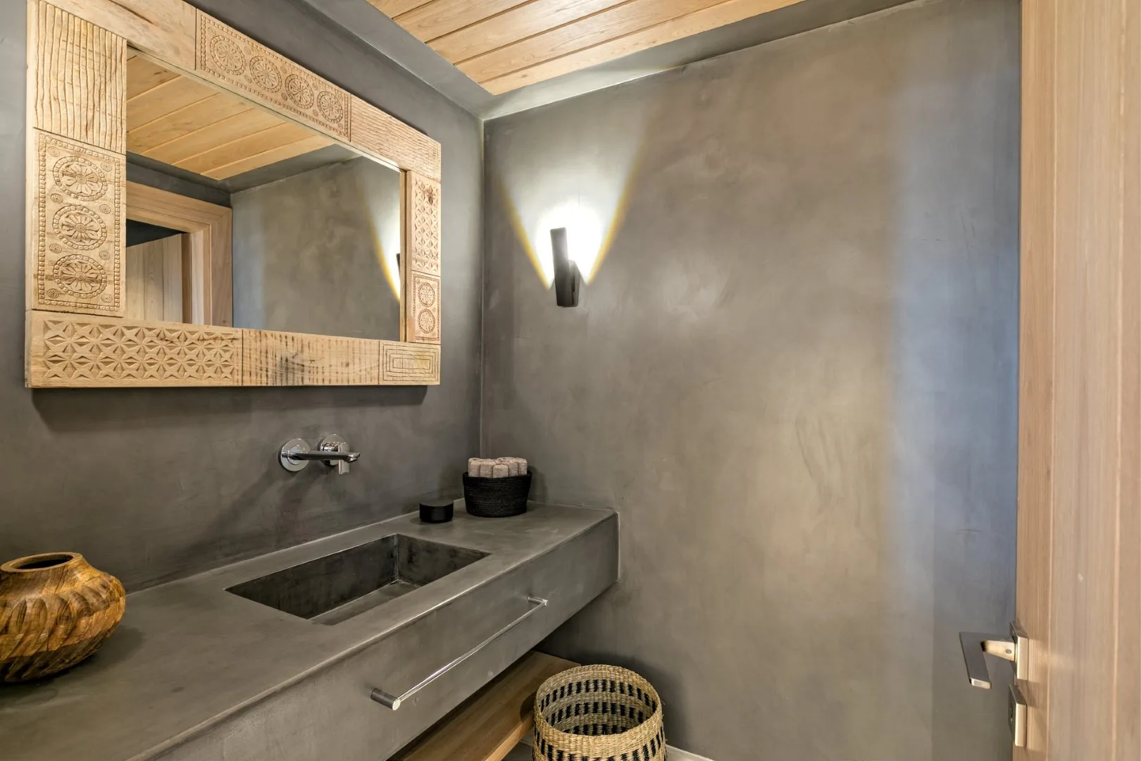 A bathroom vanity with a mirror and wall-mounted light.