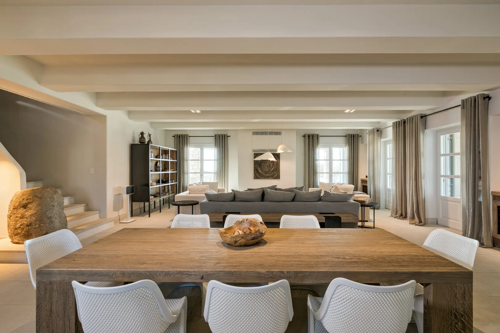 A dining area with a wooden table and seating, opening into a living room.
