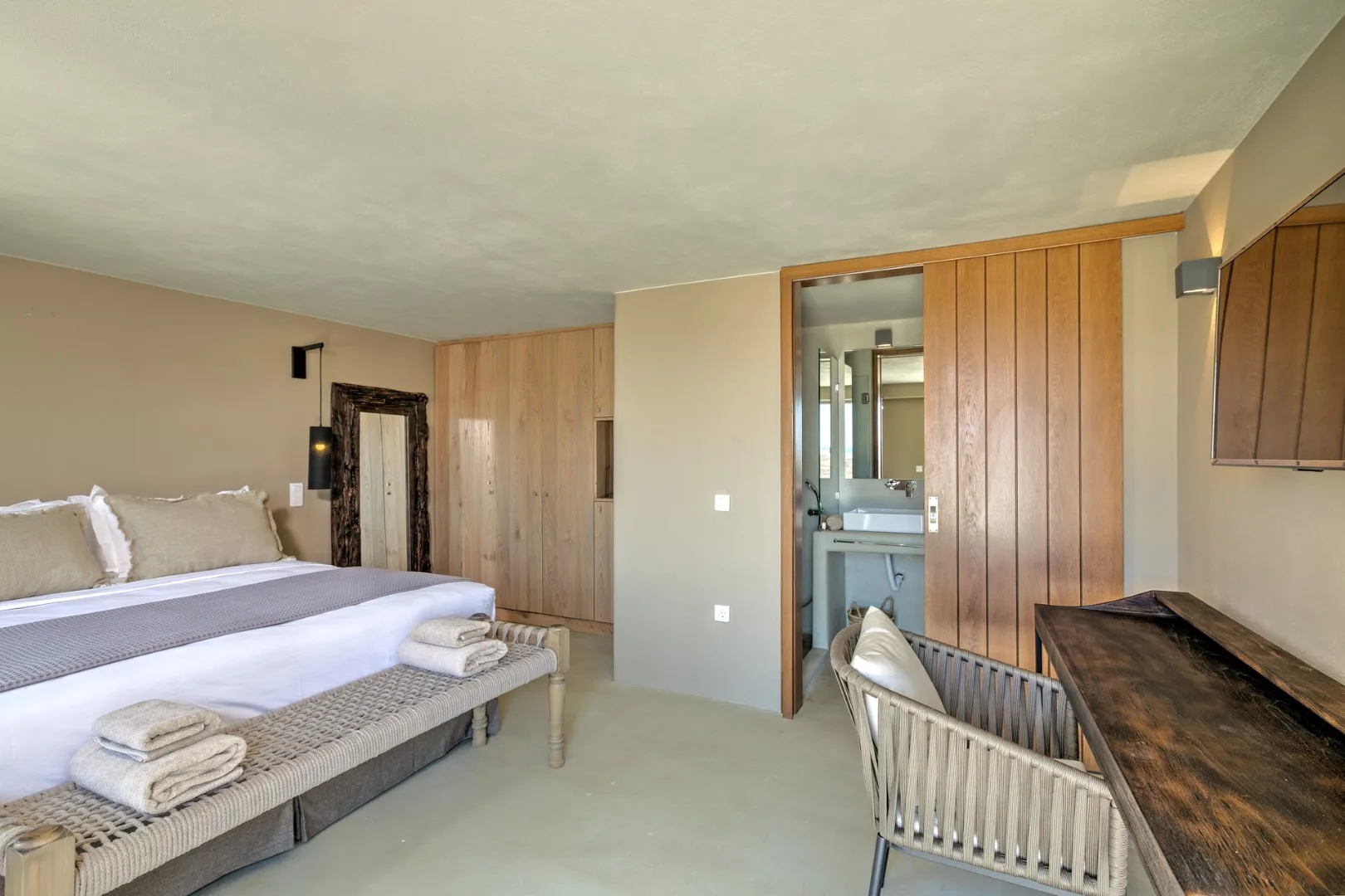 A bedroom with a bed, wooden wall panels, and an open bathroom doorway.