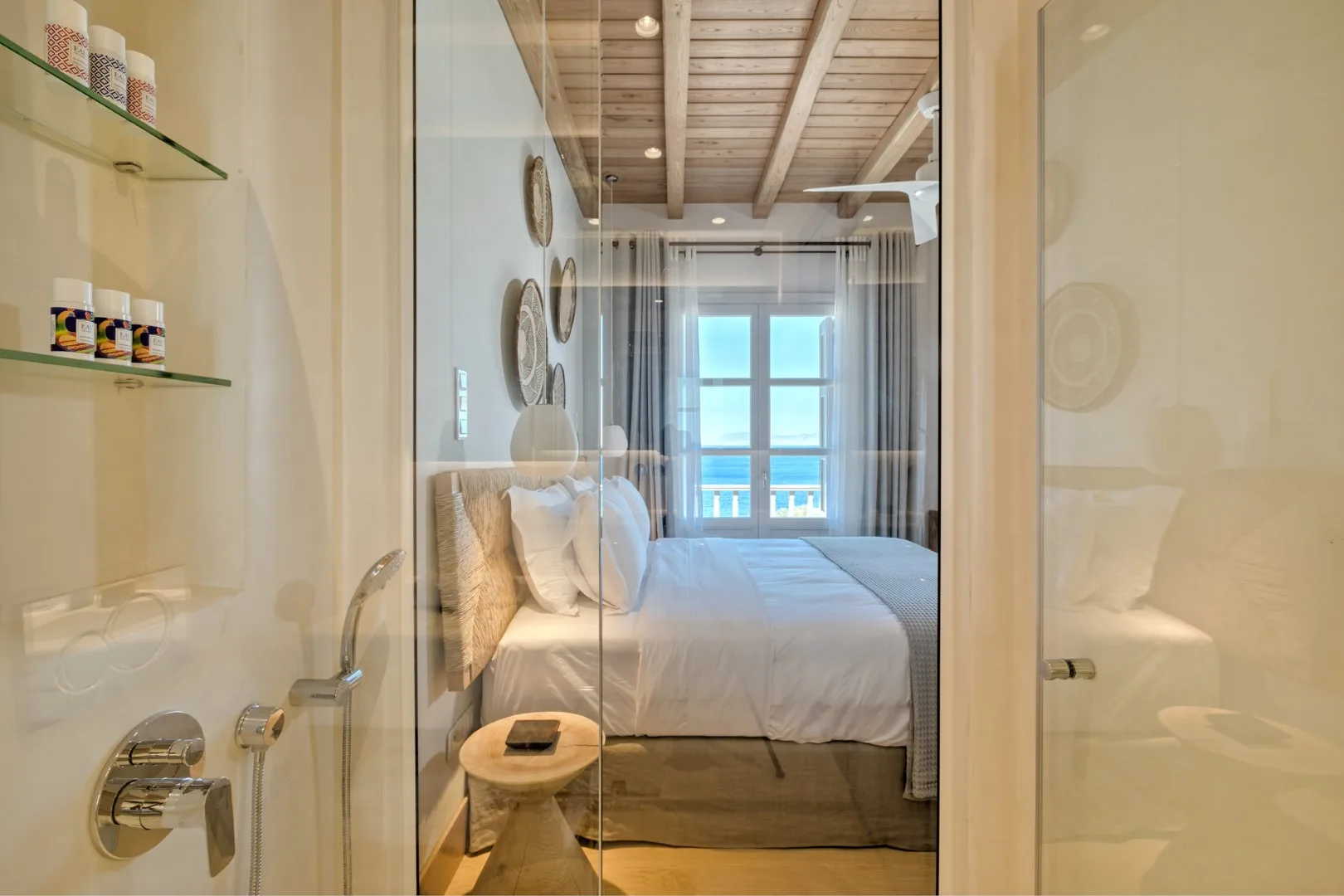 A bedroom with a neatly made bed and a large window.