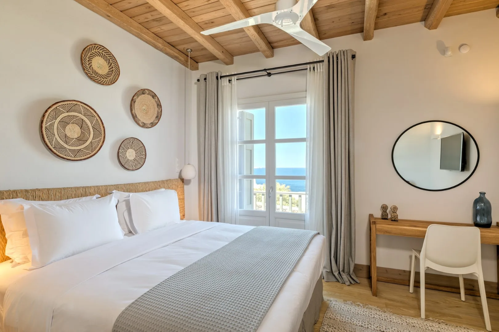 A bright bedroom with a neatly made bed beside a window.