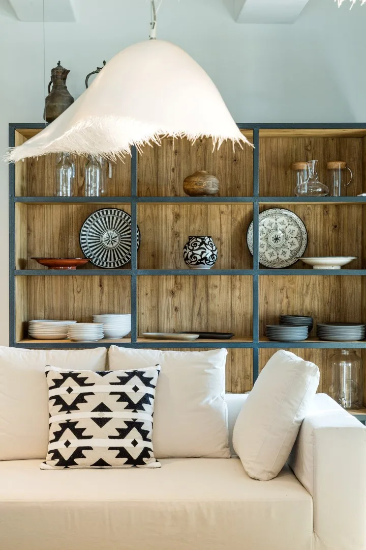 A living room seating area with a white sofa and wooden display shelves.