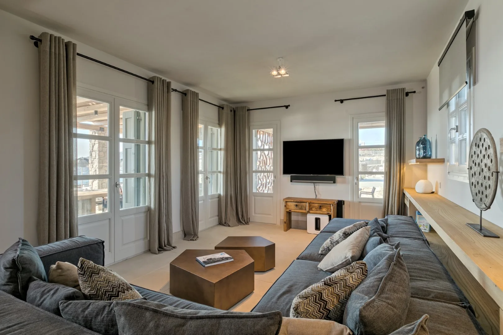 A bright living room with seating, a coffee table, and a television.