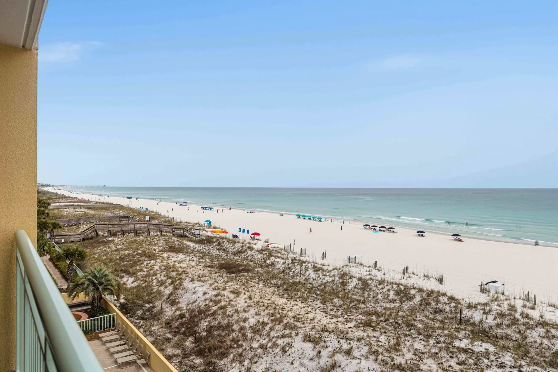 Una playa de arena y la costa se ven más allá de las dunas desde un balcón.