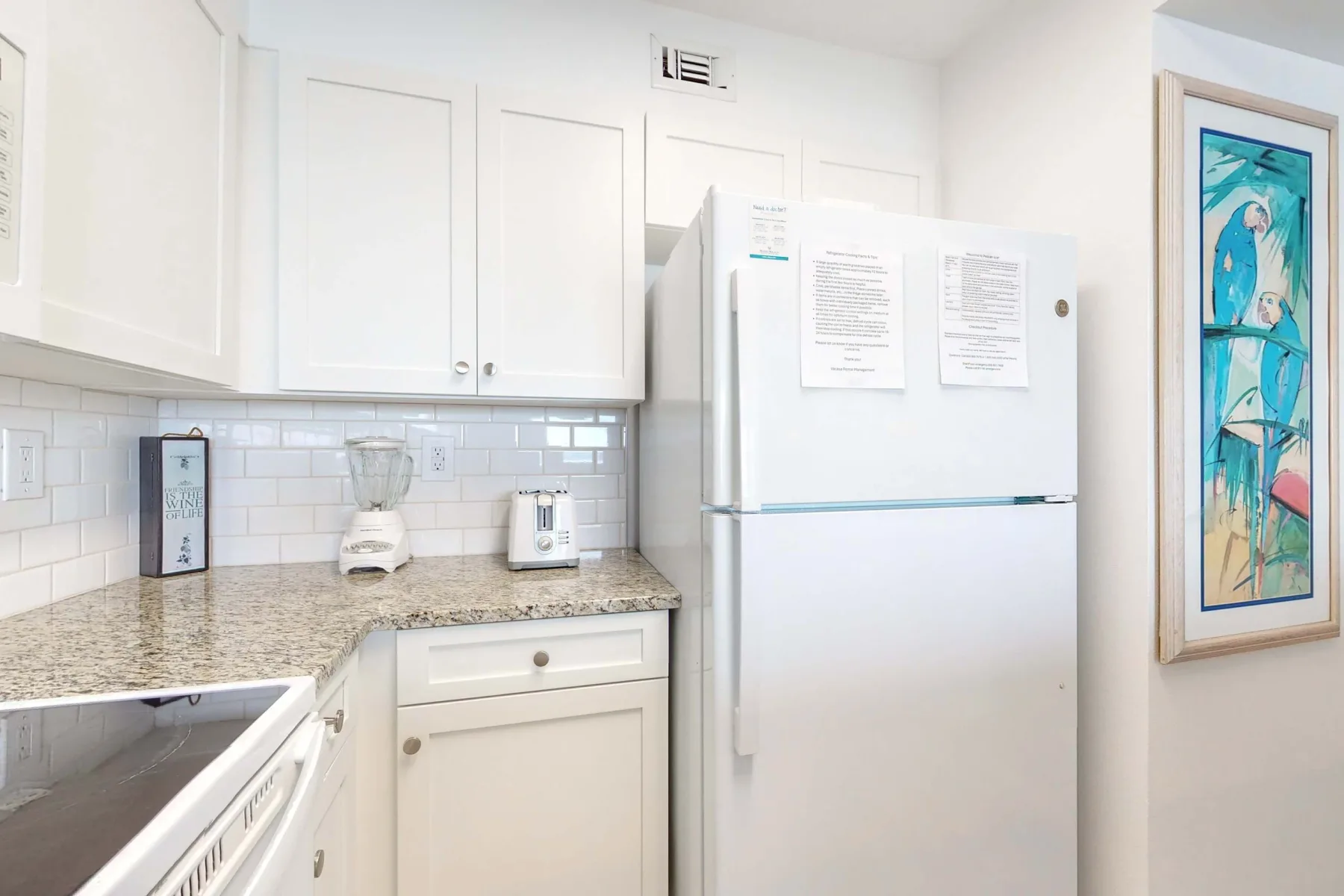 Una cocina luminosa con gabinetes blancos, una encimera y un refrigerador.