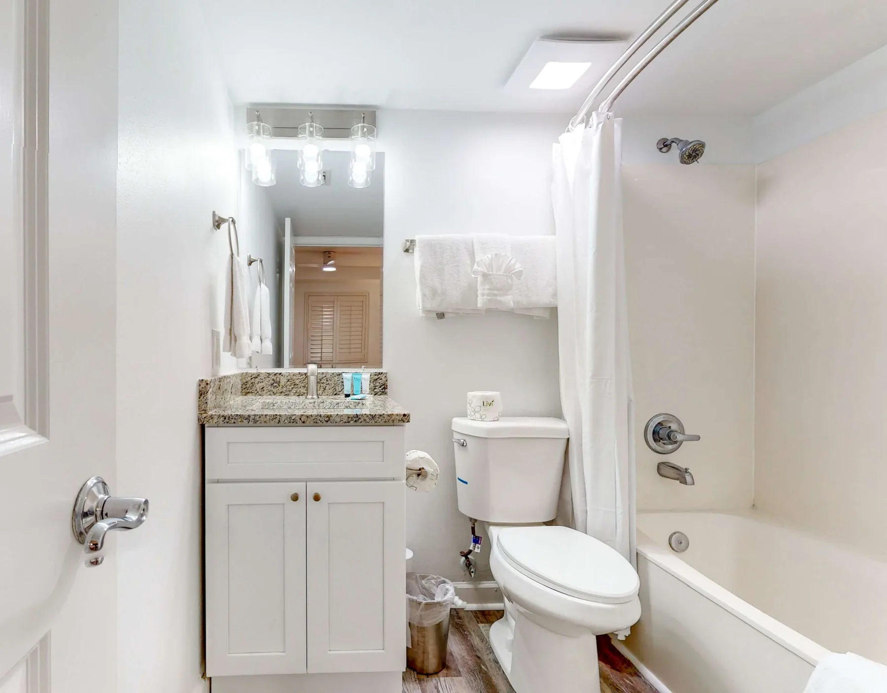 Un baño luminoso con lavabo, inodoro y bañera detrás de una cortina de ducha.