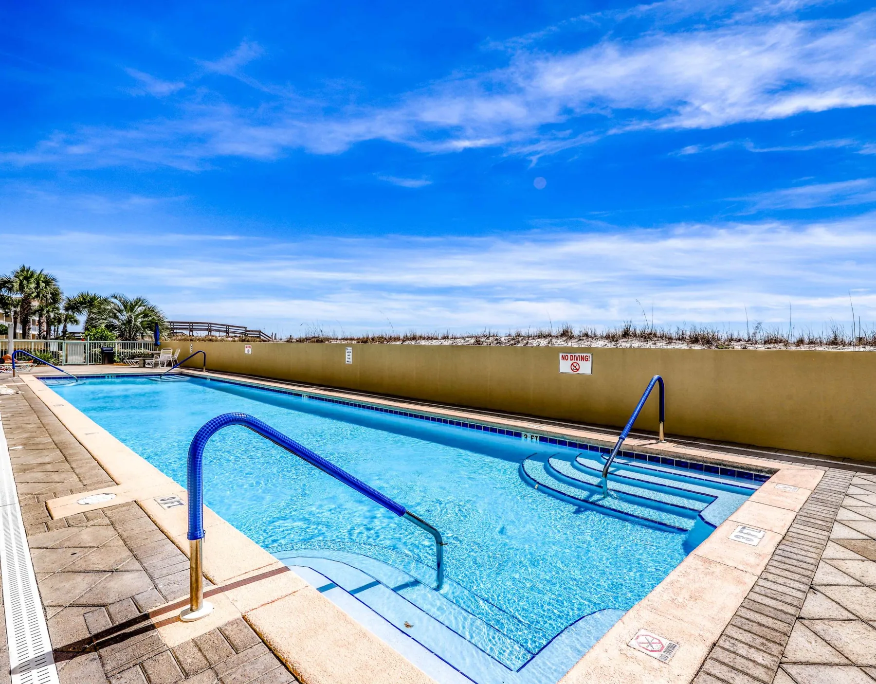 Zona común: Piscina al aire libre con agua azul y una terraza pavimentada.