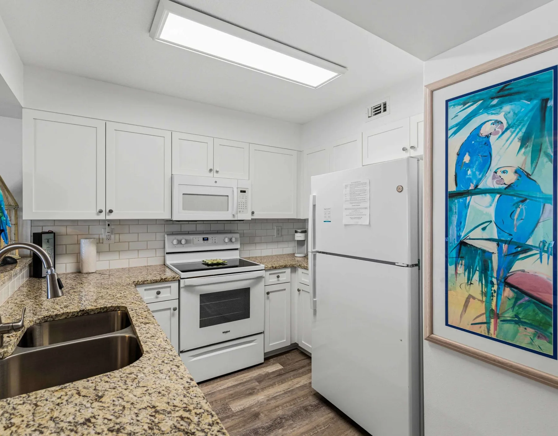 Una cocina luminosa con gabinetes blancos, una encimera y un refrigerador.