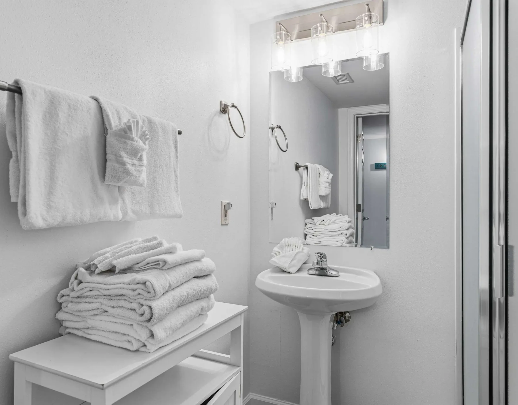 Un baño luminoso con lavabo, espejo y toallas dobladas ordenadamente.