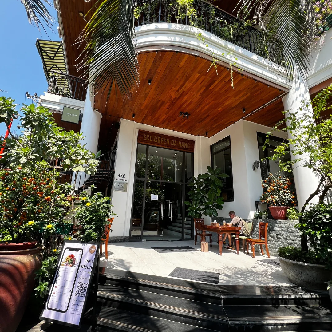 Representative hotel space: Hotel entrance beneath a wooden overhang, surrounded by potted plants.