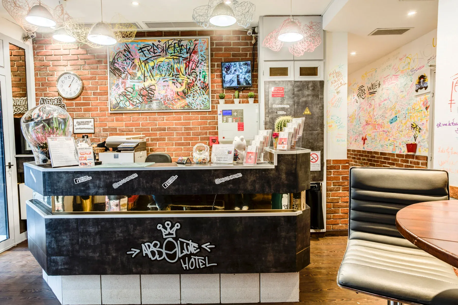 Espacio representativo del hotel: Un mostrador de recepción está en un vestíbulo de paredes de ladrillo decorado con grafitis coloridos.