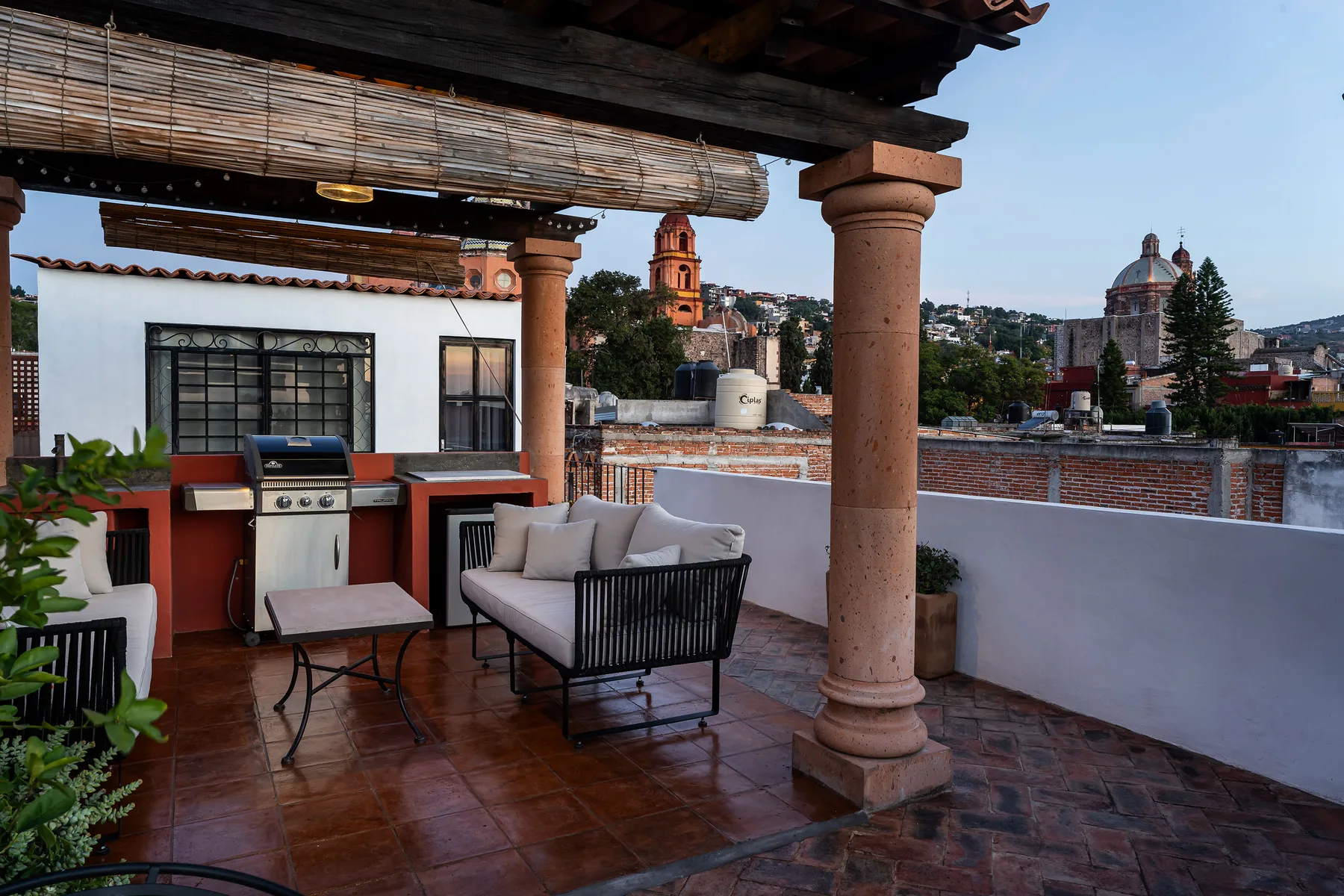 A rooftop terrace with outdoor seating and a built-in grill overlooks nearby rooftops.