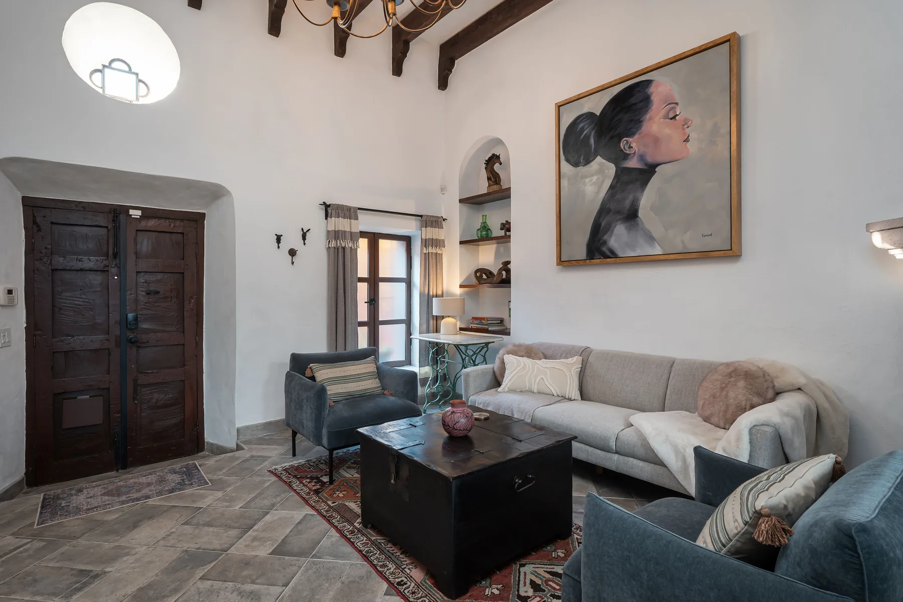 Living room with gray seating, a dark coffee table, and a large portrait on the wall.