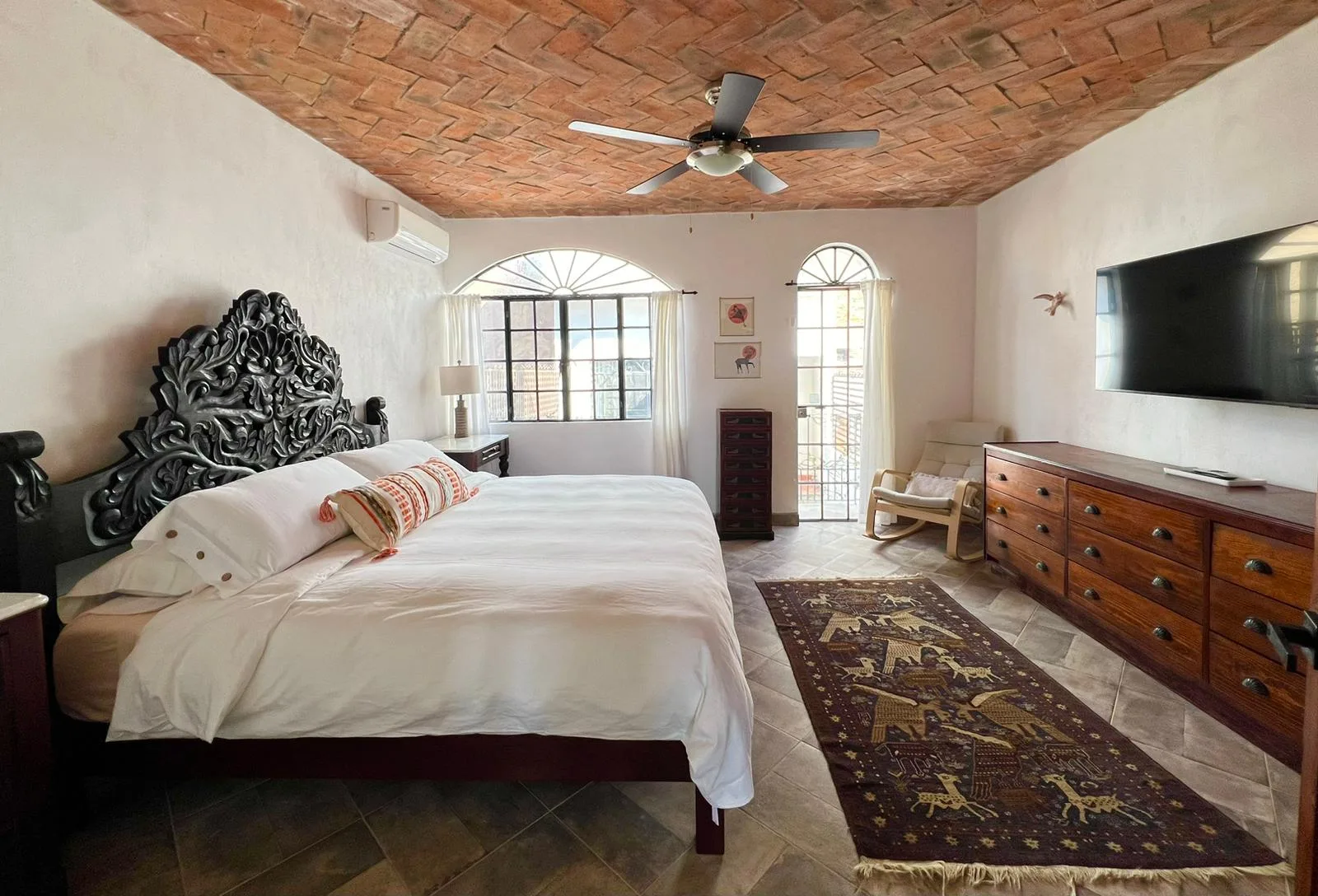 A bedroom with a bed, a wooden dresser, and a ceiling fan.