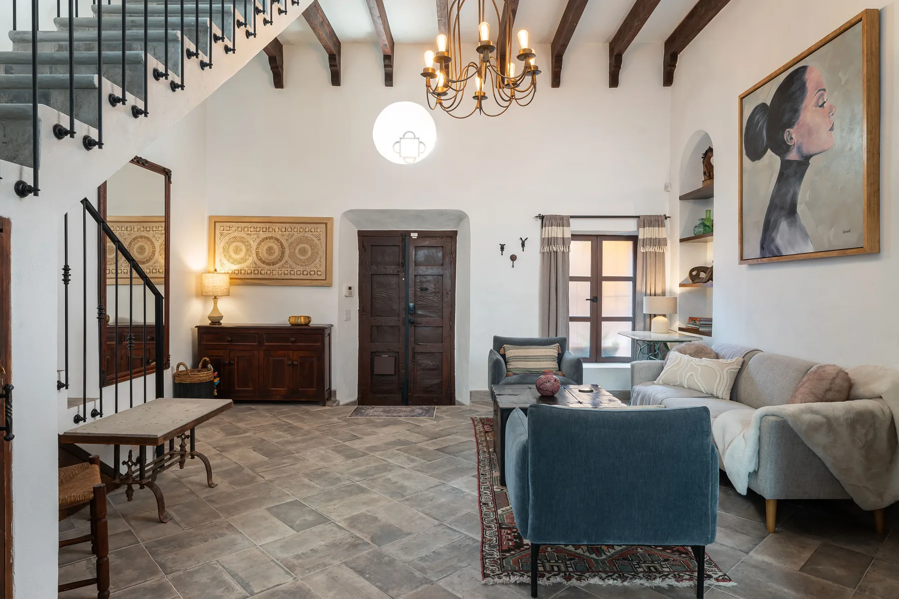 A living room with seating, a chandelier, and exposed ceiling beams.