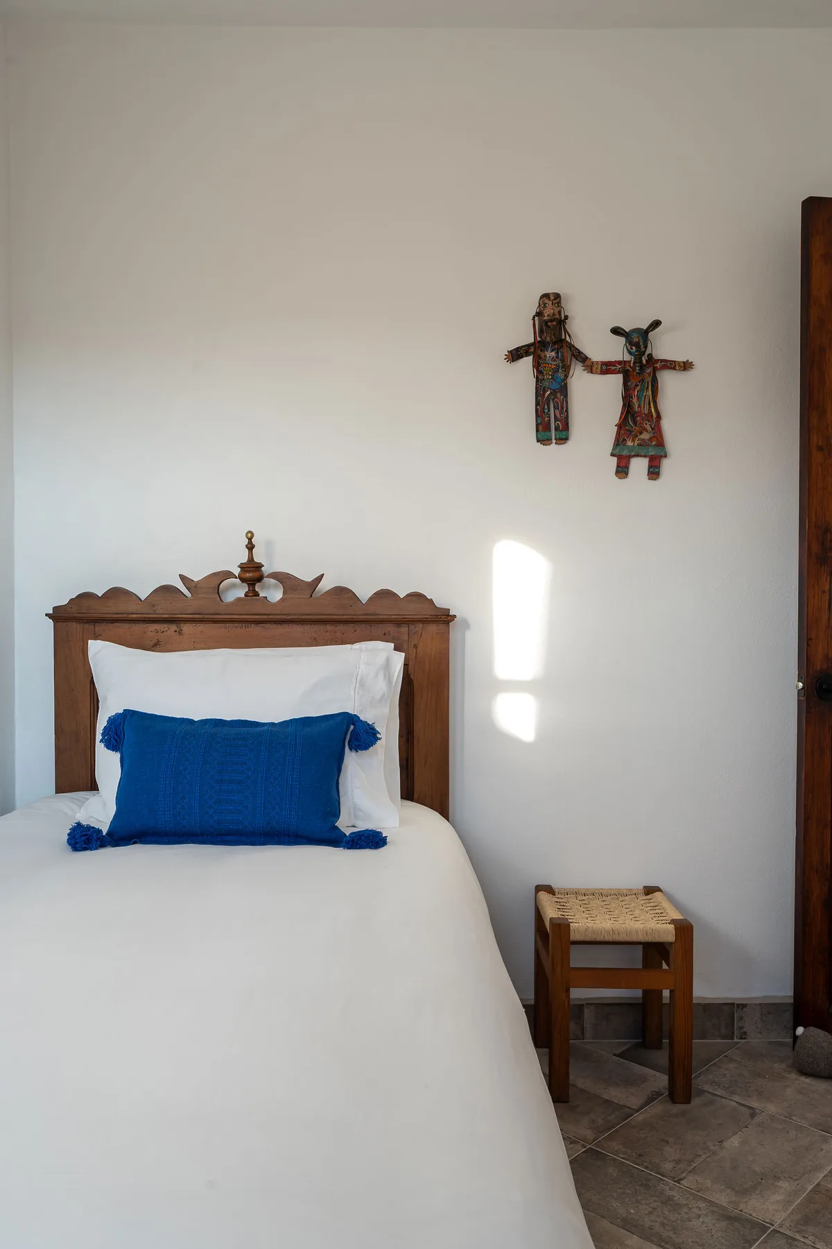A bedroom with a bed, blue accent pillow, and small wooden side table.