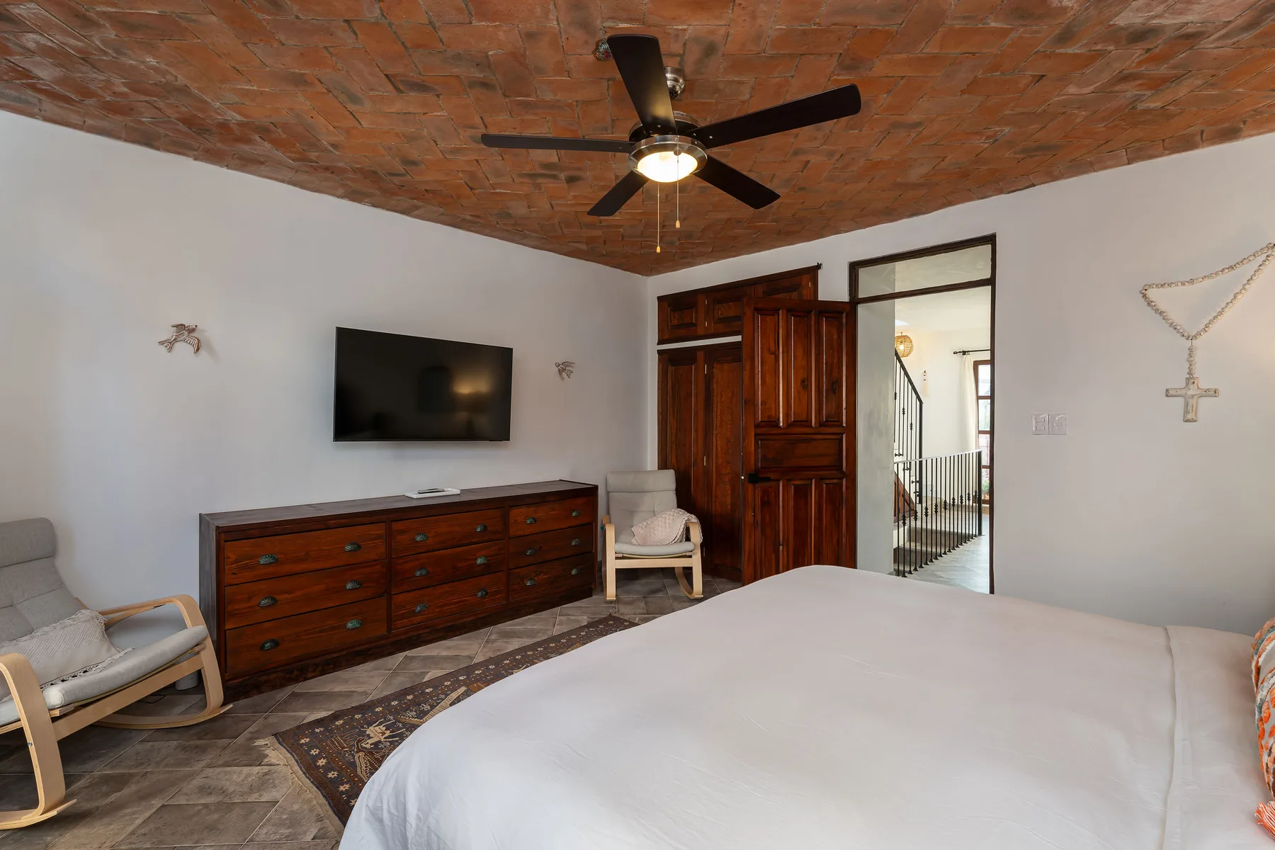 A bedroom with a bed, wooden dresser, and an open doorway.
