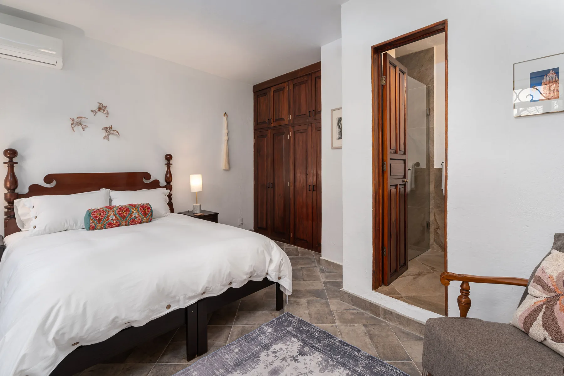 A bedroom with a wooden bed, white bedding, and a dark wardrobe.