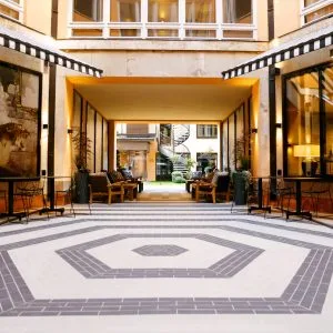 Representative hotel space: A hotel courtyard passage opens onto a tiled floor and indoor greenery.