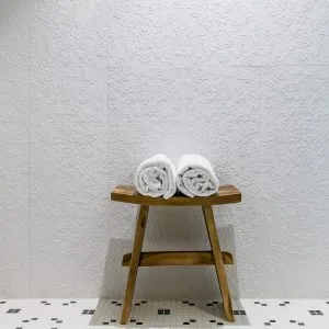 Representative hotel space: A small wooden table holds two rolled white towels against a textured wall.