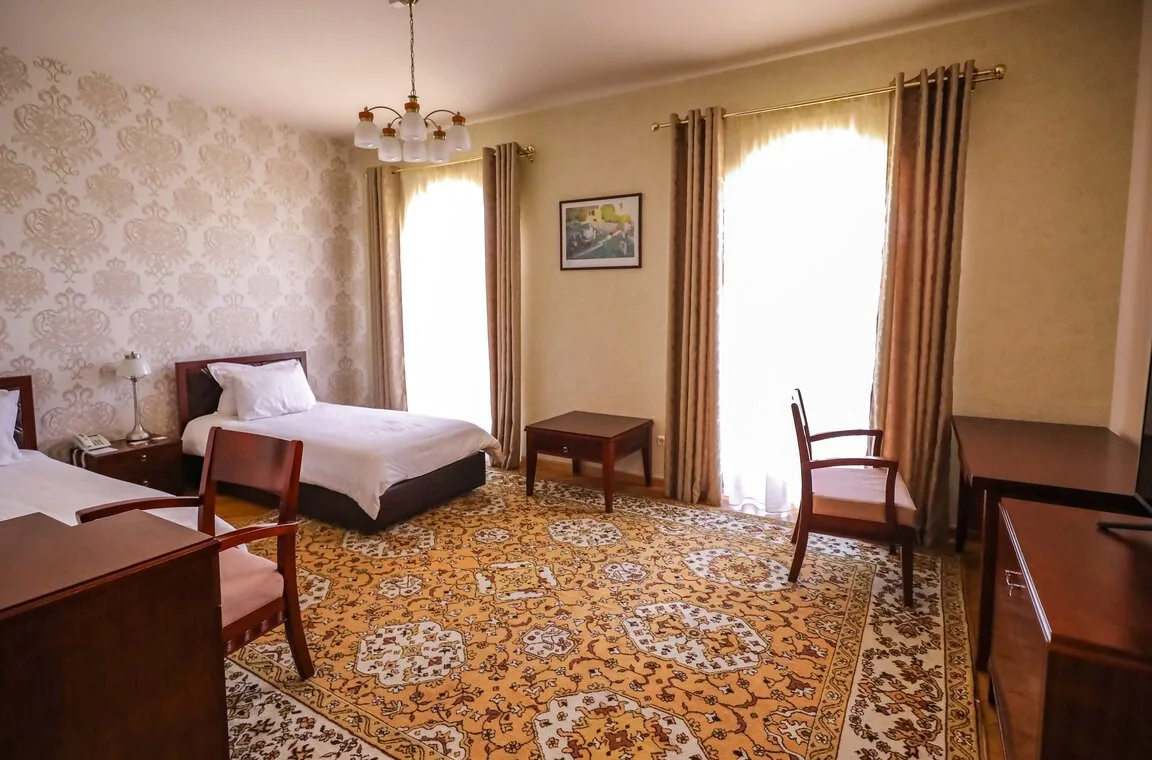 Espacio representativo del hotel: Un dormitorio amueblado con una cama, asientos y una alfombra estampada.