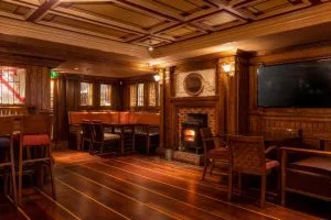 Espacio representativo del hotel: Una sala con paneles de madera, mesas, asientos y un televisor.