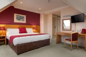 Espacio representativo del hotel: Un dormitorio de hotel con una cama, lámparas de mesilla y un escritorio junto a la ventana.
