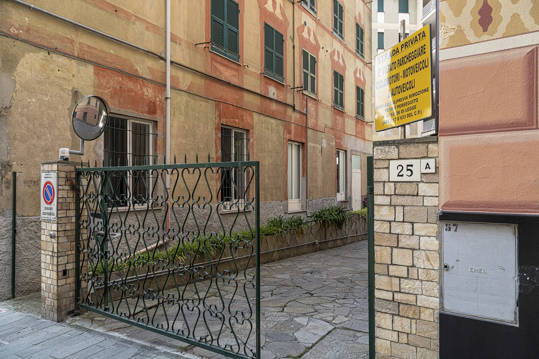 Zona común: Un pasaje de entrada pavimentado pasa entre edificios de apartamentos, con una verja metálica.