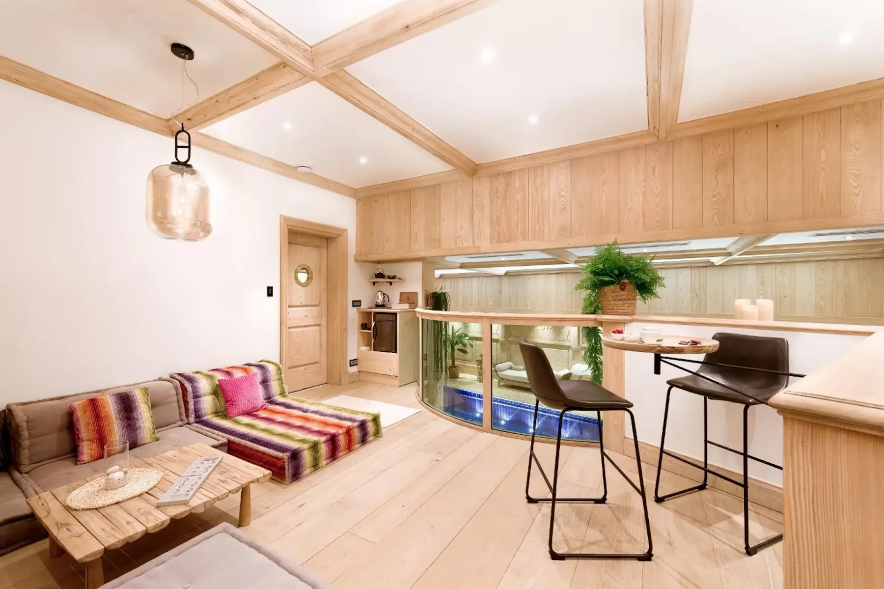 Una luminosa sala de estar de planta abierta con asientos coloridos junto a una barra de cocina.